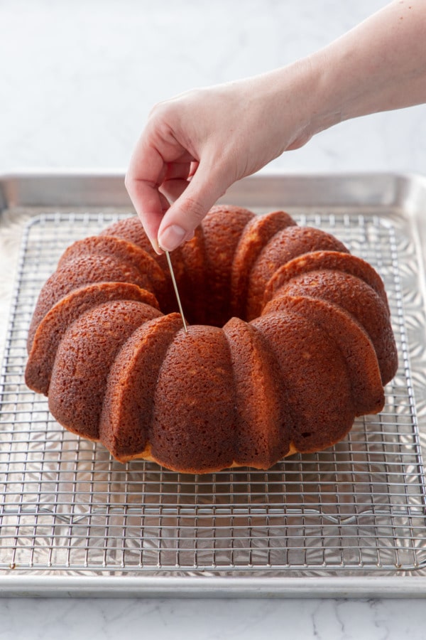 Poking the still-warm cake with a skewer all over the surface.