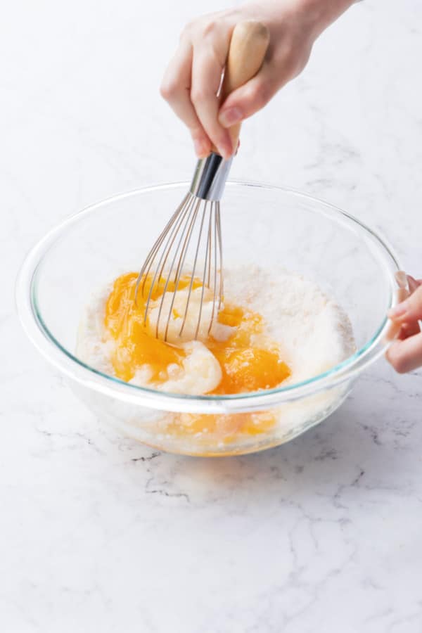 Whisking eggs into granulated sugar with a wire whisk.