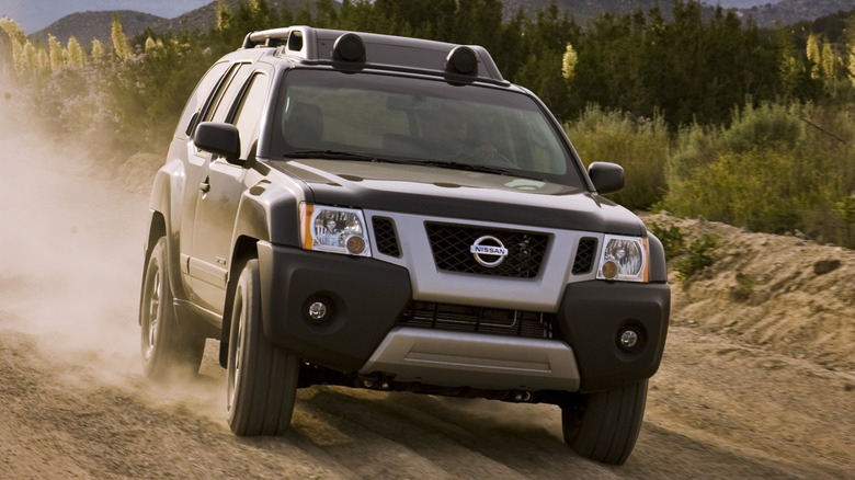 A black XTerra from the front driving on a sandy path