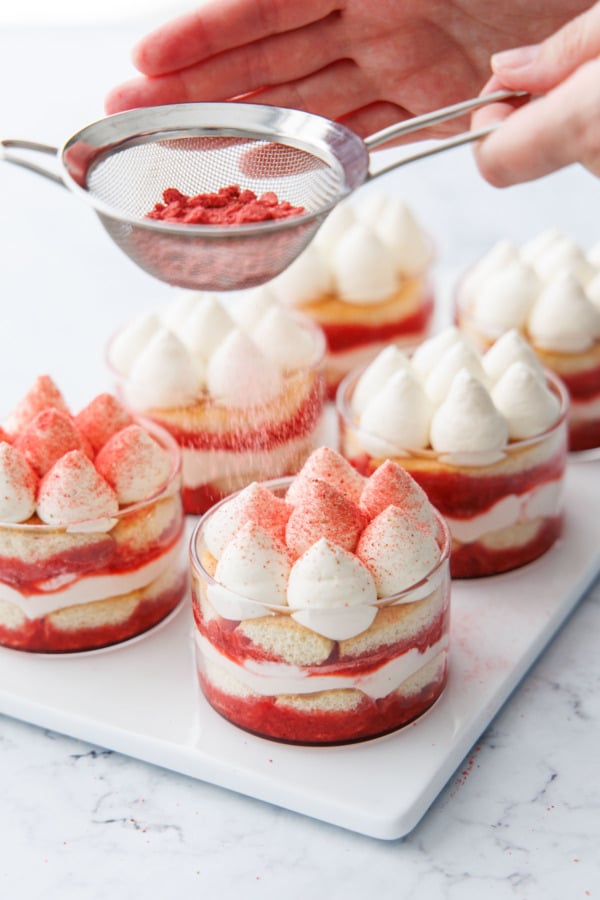 Dusting the tops of the strawberry tiramisu with freeze dried strawberry powder.