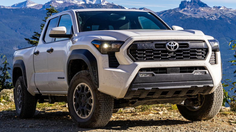 A white Toyota Tacoma parked in front of a mountain range.
