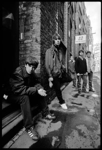 British rock band Oasis (Noel Gallagher, Liam Gallagher, Paul McGuigan, Paul Arthurs, Tony McCarroll) on Flitcroft St, London WC2, 15 March 1994