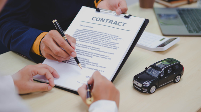 Two people preparing to sign a car purchase contract.
