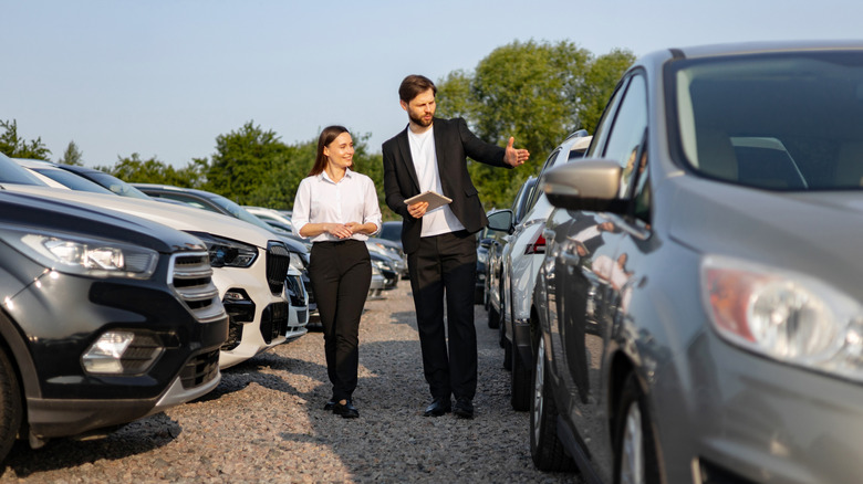 Two people walking among cars at a dealership.