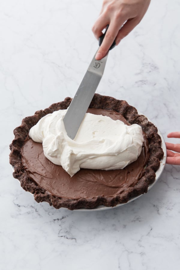Topping the chilled pie with a layer of fluffy whipped cream.