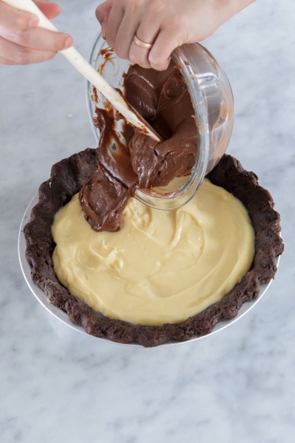 Pouring the chocolate custard on top of the vanilla custard layer in the pie crust.