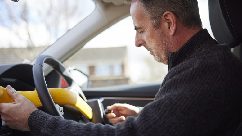 Man installing a manual steering lock to deter thieves